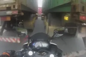 鲁莽！巴西摩托车手不愿等待从两卡车缝中穿行 车轮被卡车压扁图片