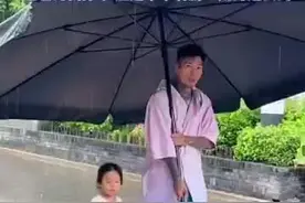 显眼包爸爸举遮雨棚接女儿放学图片